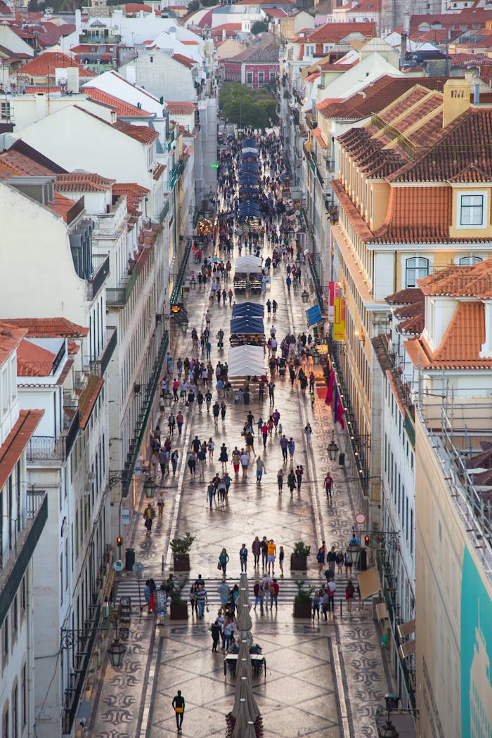 A bustling aerial view of a busy street in Lisbon, Portugal, lined with historic buildings and vibrant activity.